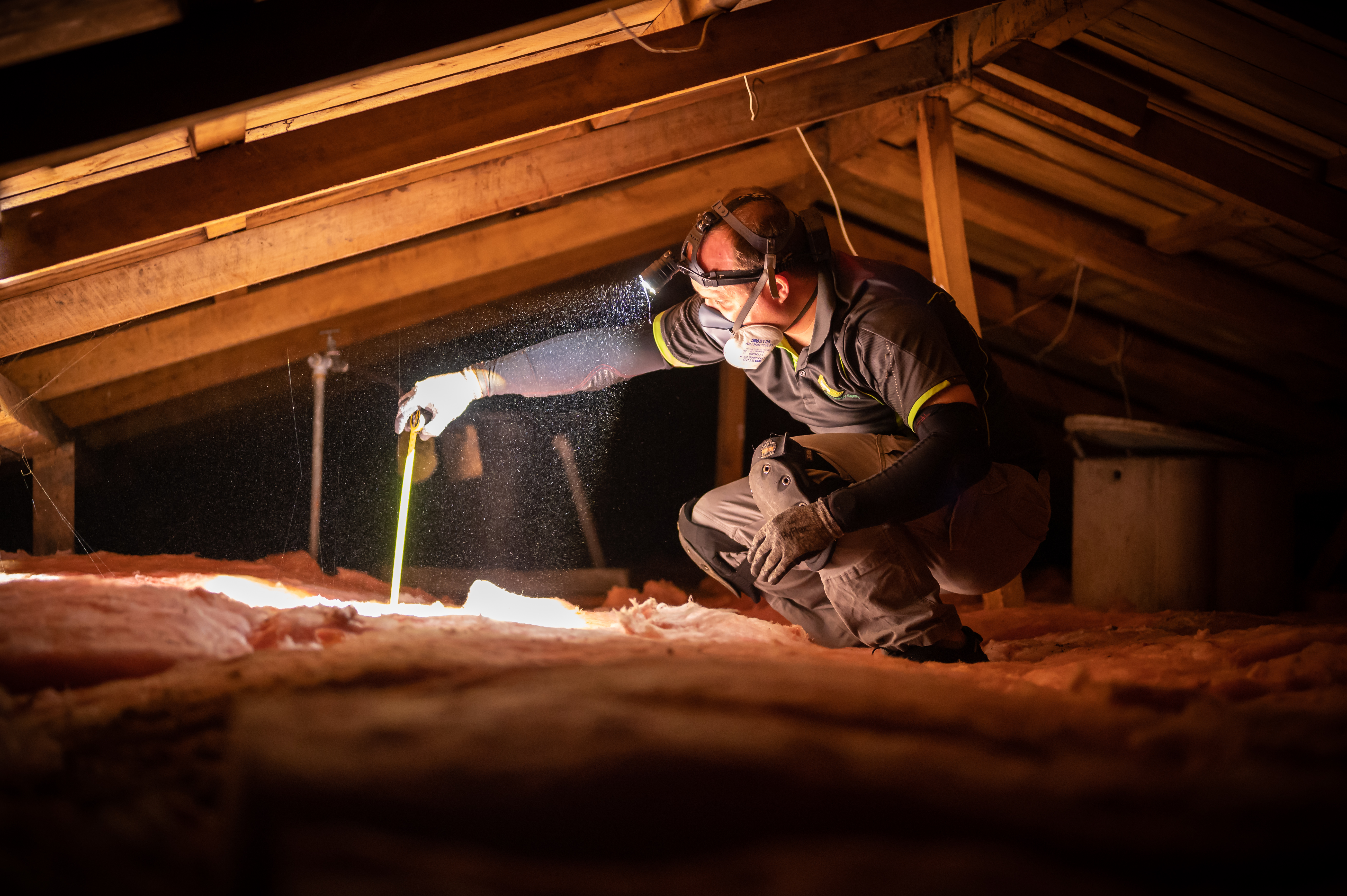 EnergySmart assessor checks ceiling insulation in home for eligibility testing.